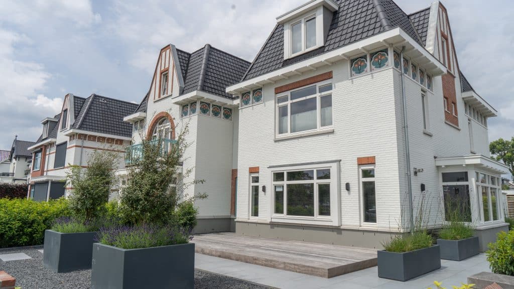 Vier hoogwaardig afgewerkte villa’s met witte bakstenen en een zwart dak. De gevels zijn met oranje bakstenen en kleine bloemen kunstwerken afgewerkt. Het eerste en meest prominente huis heeft 4 grote ramen (drie onder en 1 boven) en een extra uitsnede met glas aan de rechterkant. Er zijn ook vier donkergrijze plantenbakken met daarin lavendel. De huizen worden gescheiden met een groene struik.