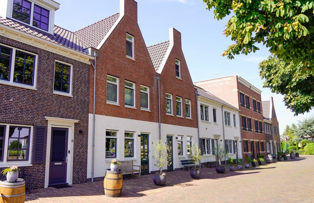 Een foto van de nieuwe moderne huizen op de Nesse nummer 24-34. De voorkanten van de huizen zijn verschillend opgebouwd, waarbij de ene donker en de ander licht zijn. Er staan plantenbakken voor de deur.