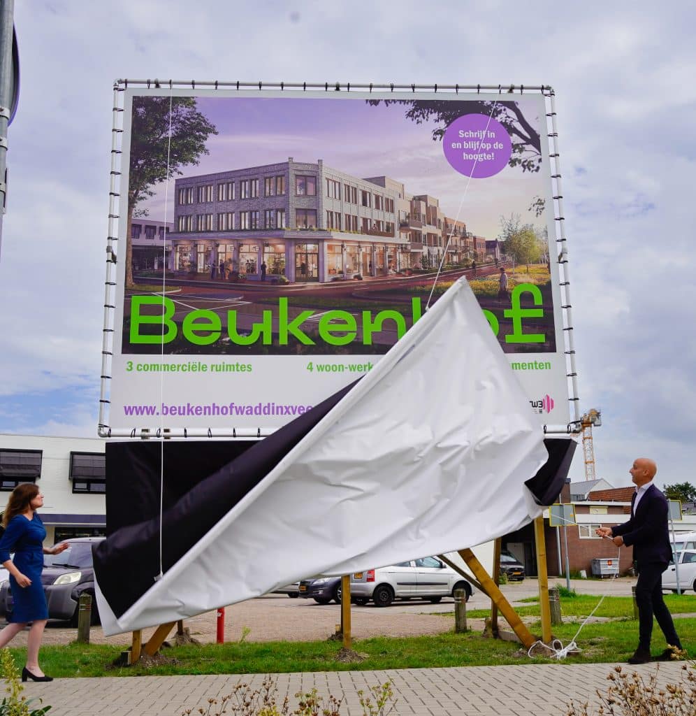 Het bouwbord van de Beukenhof wordt onthuld door wethouder Femke Vleij en ontwikkelaar Tomas van den Berg. Op het bord is het ontwerp van de Beukenhof te zien.