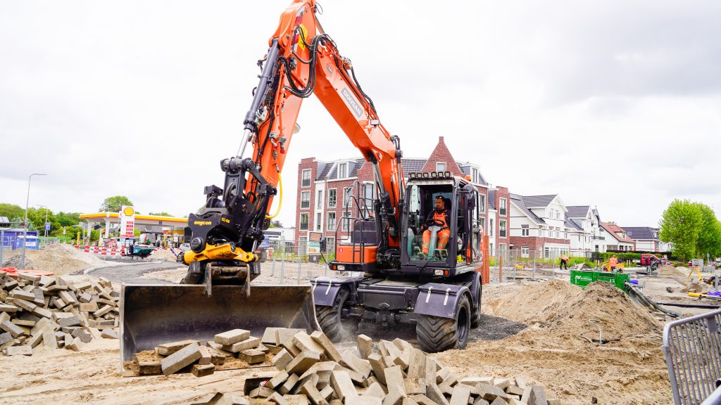 Graafmachine zichtbaar die bezig is met graafwerkzaamheden op de rotonde.