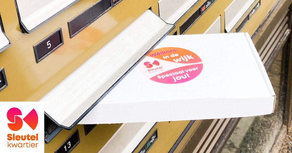 Een doosje half uit de brievenbus gestoken. Met een sticker erop: Welkom in de Wijk! Speciaal voor jou!