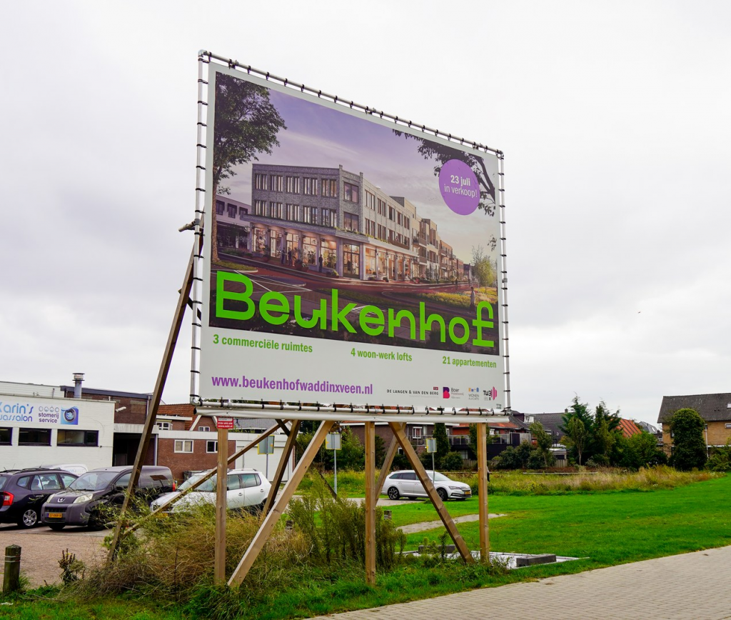Banner met toekomstige gebouw zichtbaar op de plek waar appartementencomplex komt te staan.