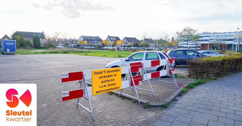 Foto van parkeerterrein waar de Beukenhof gebouwd gaat worden. Er staat een afzethek met een bord erop met de tekst: Vanaf 5 november verboden te parkeren i.v.m. bouwwerkzaamheden.